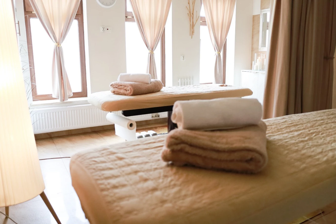 Gabinet masażu w salonie Good Time z dwoma łóżkami i dużymi oknami